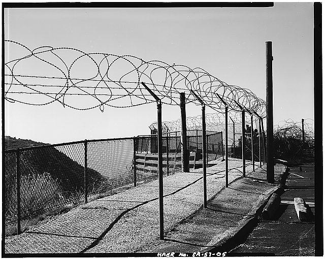 VIEW SHOWING DOUBLE FENCE AROUND LAUNCH AREA, 004. ANOTHER BARBED WIRE FENCE IS LOCATED AT BASE OF RETAINING WALL